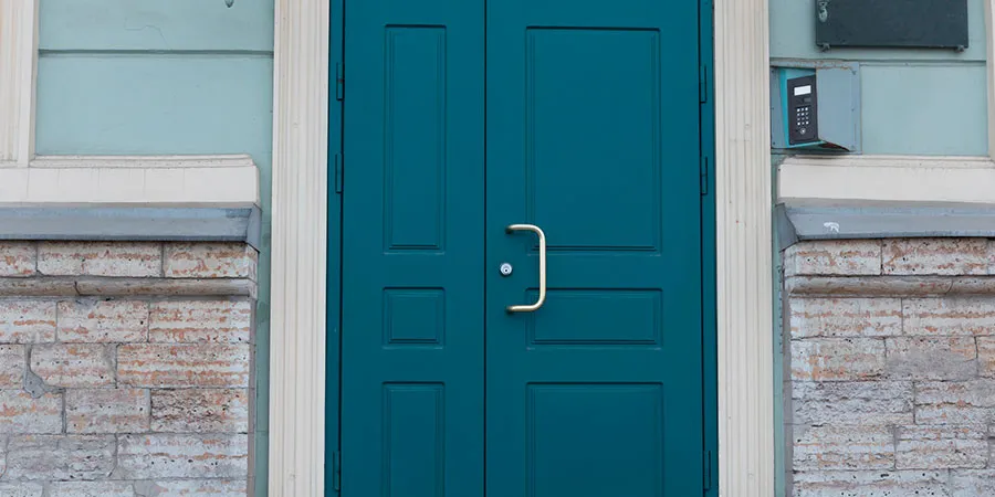 Porte d'entrée à deux vantaux bleu canard, sur une façade en pierre